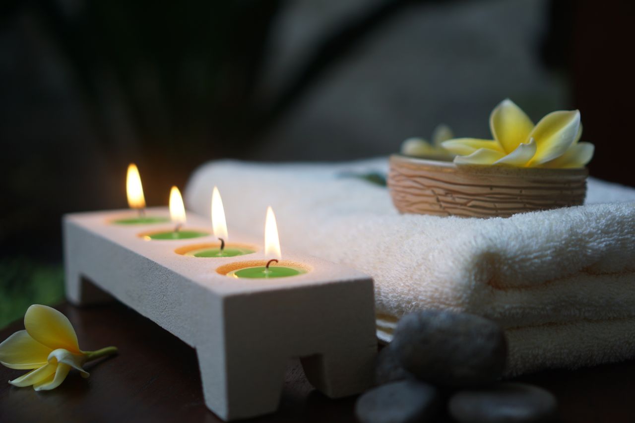 Home Relaxing spa scene featuring flickering candles, soft towels, and fresh flowers.