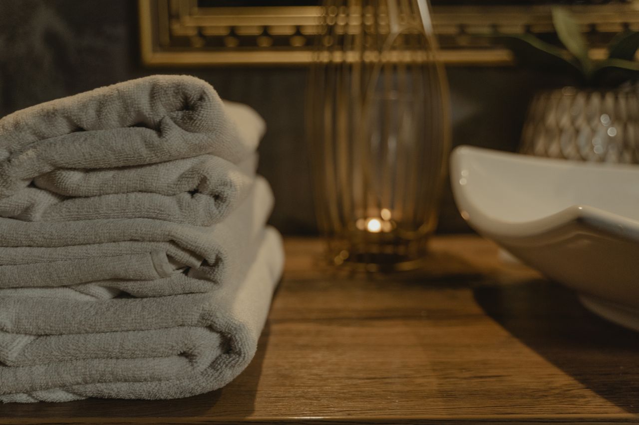 Home Elegant white towels neatly stacked in a cozy bathroom ambiance with soft lighting.