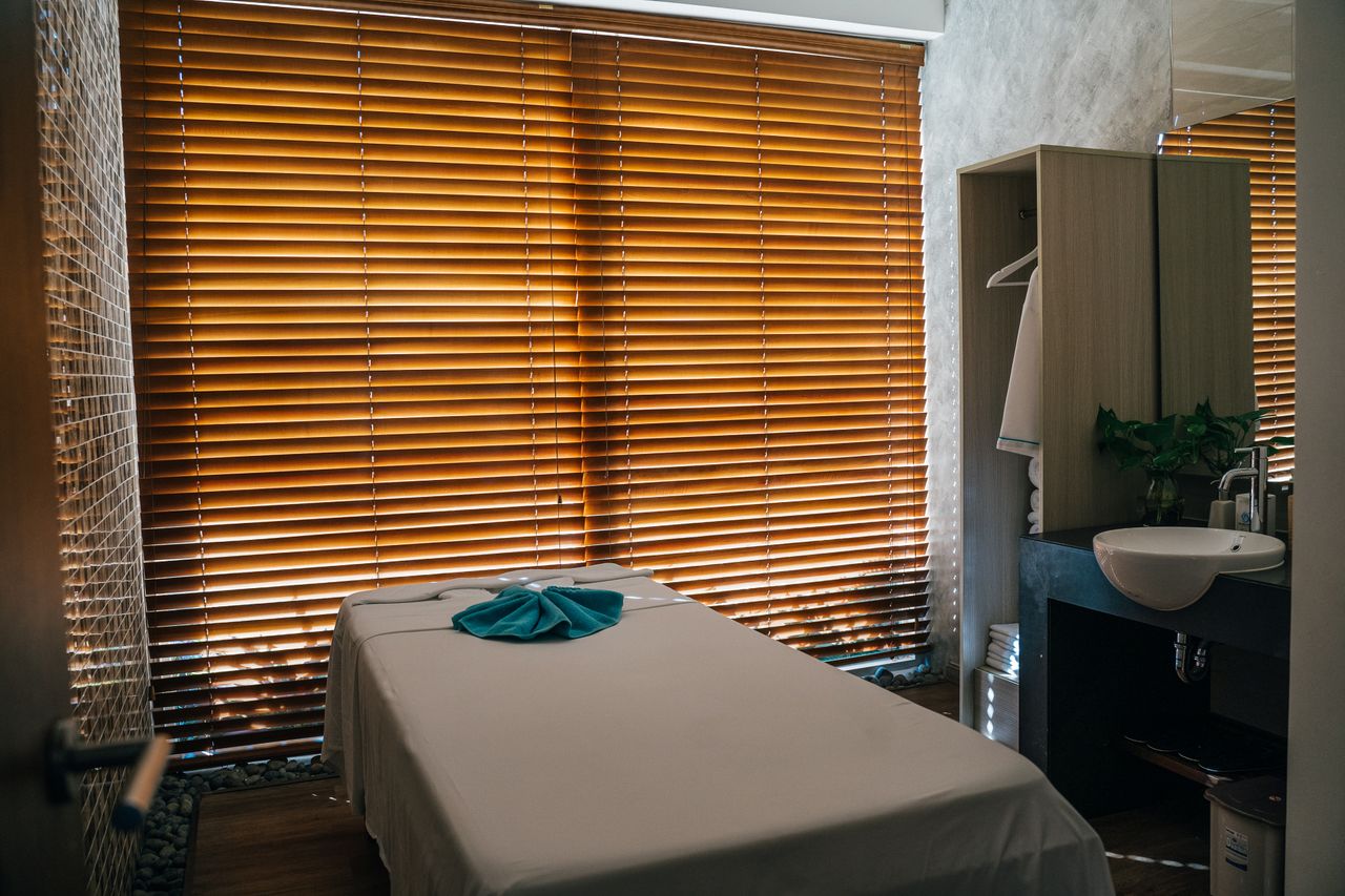 Home A tranquil massage room with natural light and neatly arranged furnishings for relaxation.